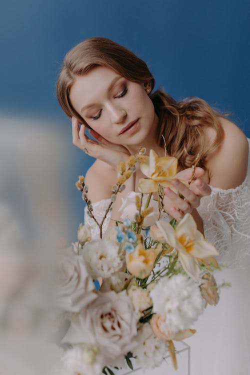 Photo of a Bride Touching a Flower
