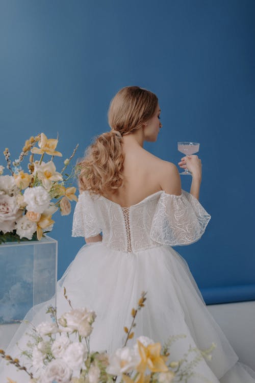 Back View of a Woman in White Lace Dress Holding a Coupe Glass