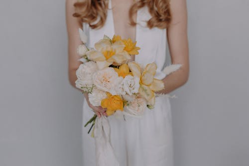 Woman in White Dress Holding White and Yellow Flower Bouquet