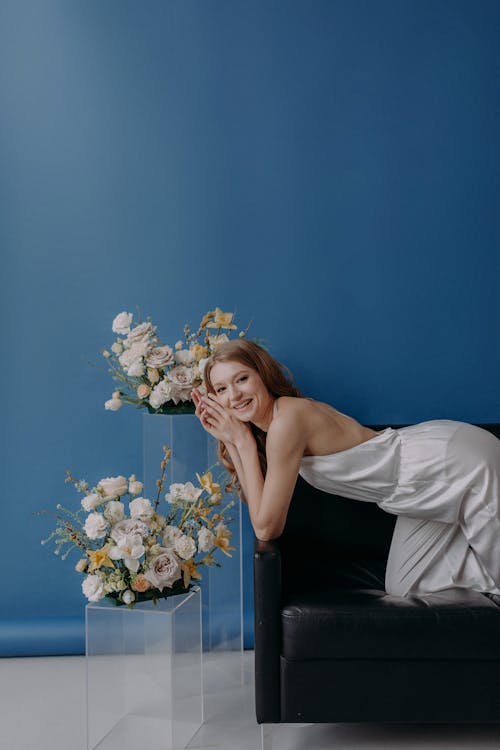 Model in a Long White Backless dress Posing on a Black Sofa