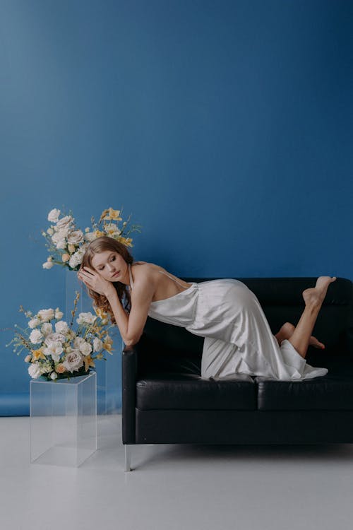 A Woman in White Jumpsuit Sitting on Black Couch