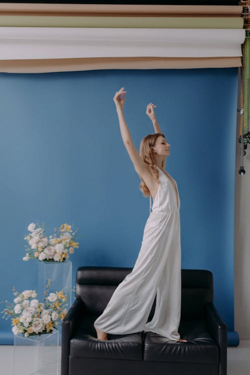 Woman in White Sleeveless Dress Standing on Black Chair