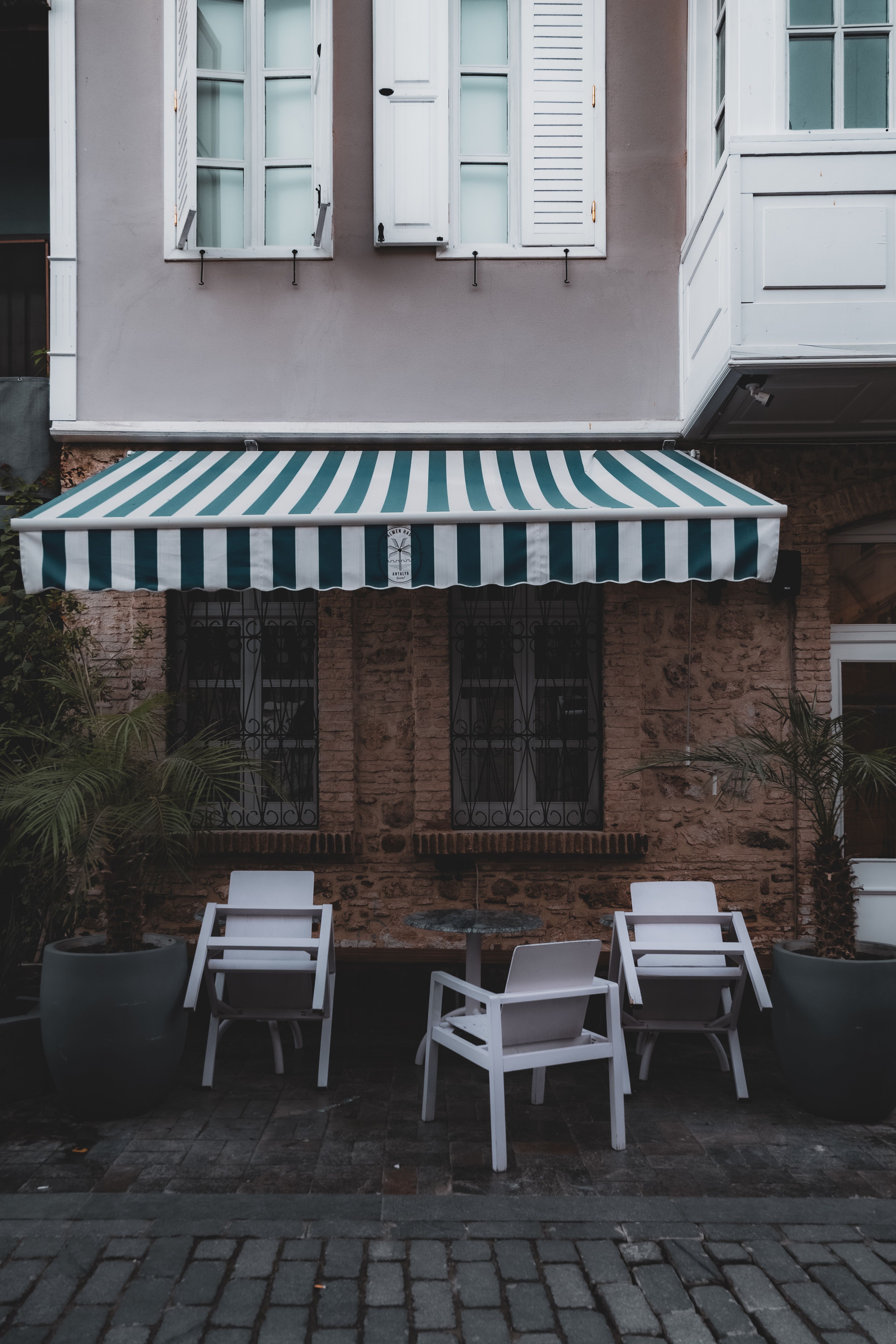 retractable fabric side awning extending from a home wall to block views on a small patio