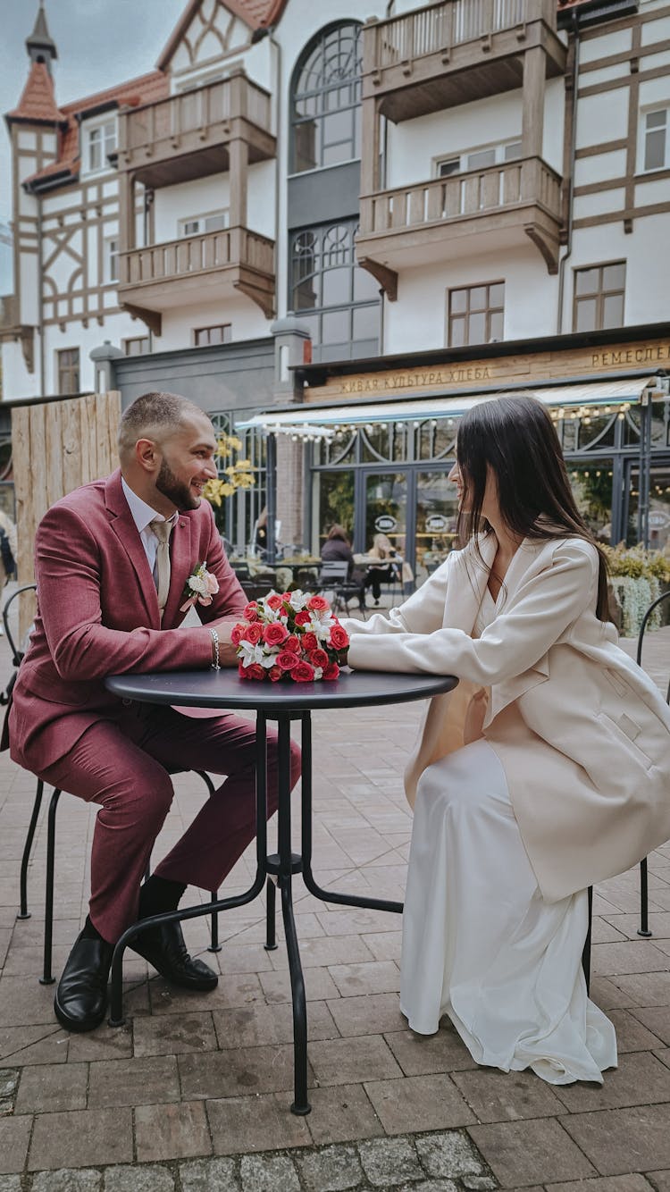 A Couple Sitting At An Outdoor Dining Table