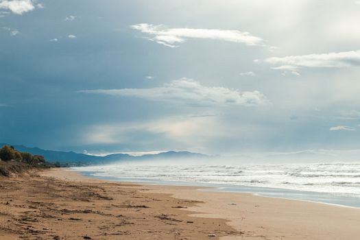 Peaceful beach scene featuring a cloudy sky and waves lapping at the sandy shore.