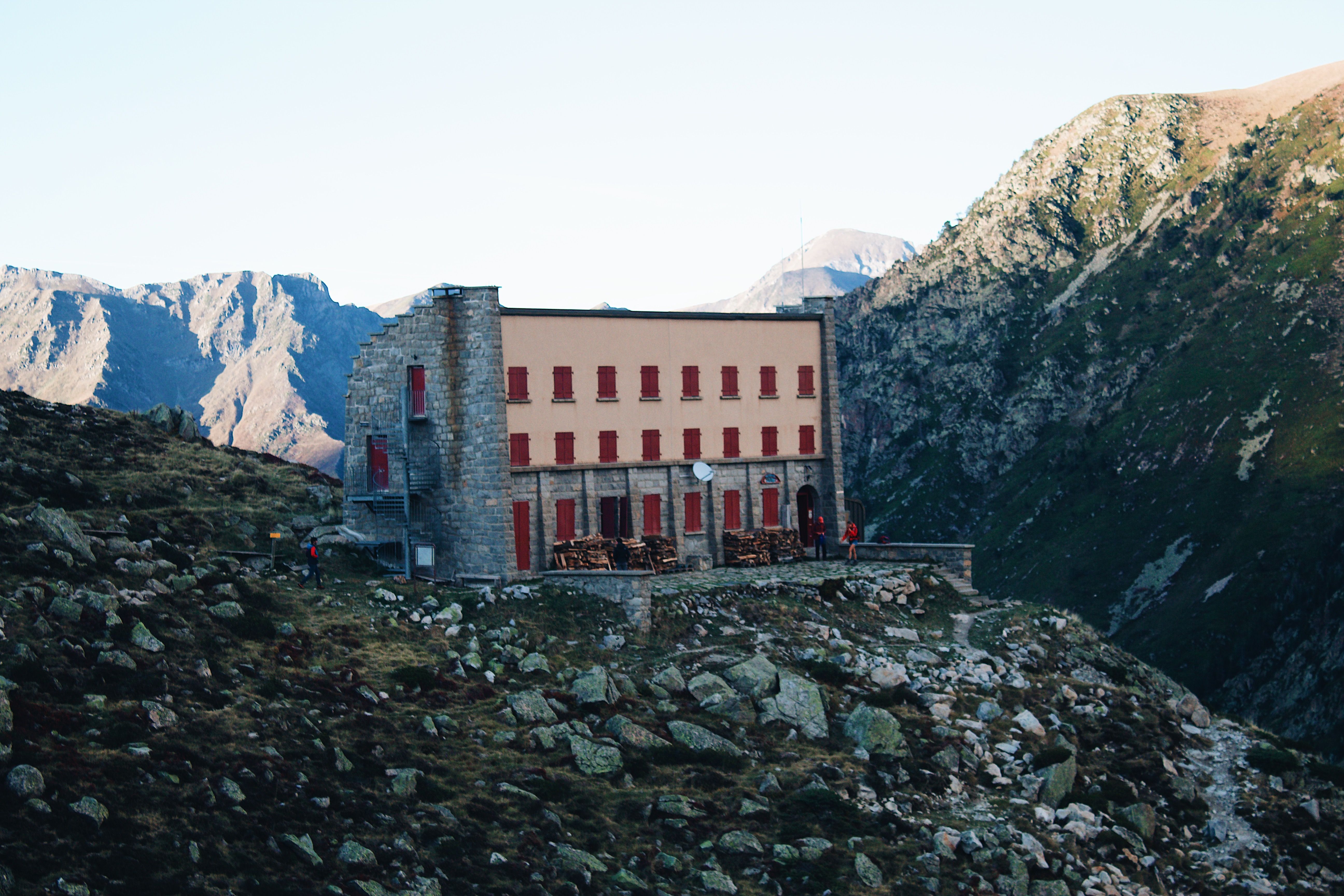 A remote mountain lodge nestled in a rocky landscape under clear skies.