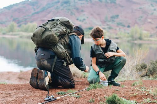 Free Father and son bonding over a fishing trip by a serene lake in an outdoor setting. Stock Photo