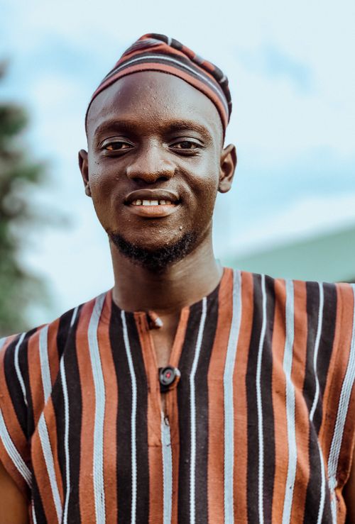 Free Portrait of a smiling African man wearing traditional attire, outdoors. Stock Photo