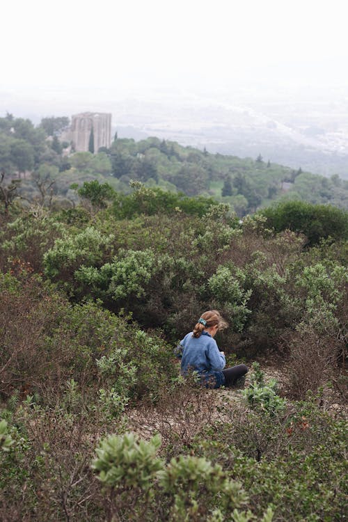 A Girl Sitting on the Ground with Bushes