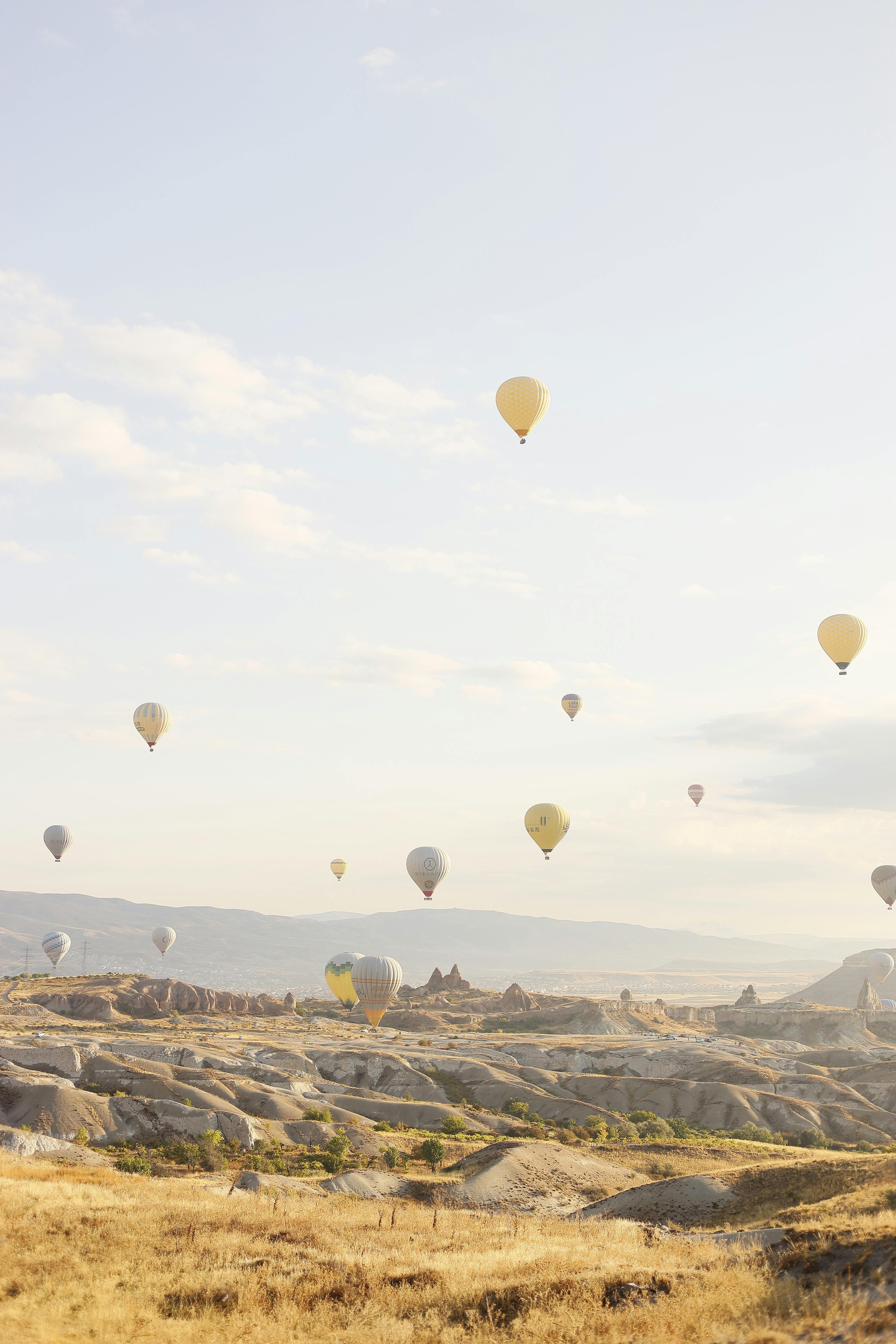 Stunning view of hot air balloons floating over Cappadocia's unique rock formations at sunrise.