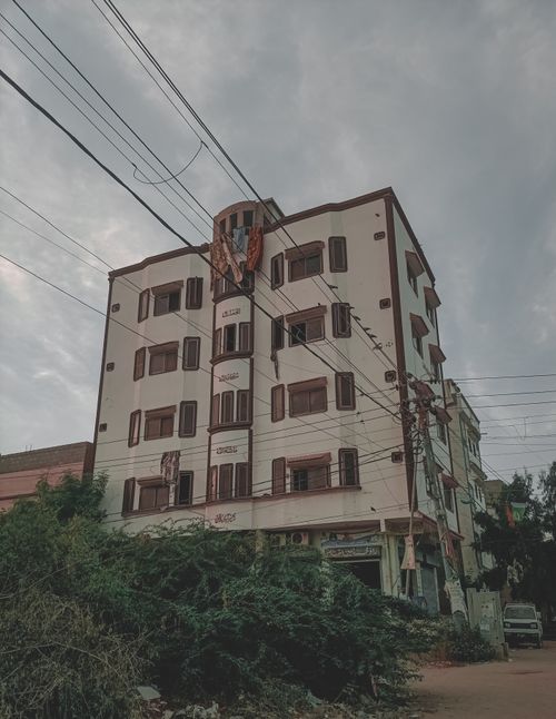 Free Exterior view of a city apartment building with visible utility wires on a cloudy day. Stock Photo