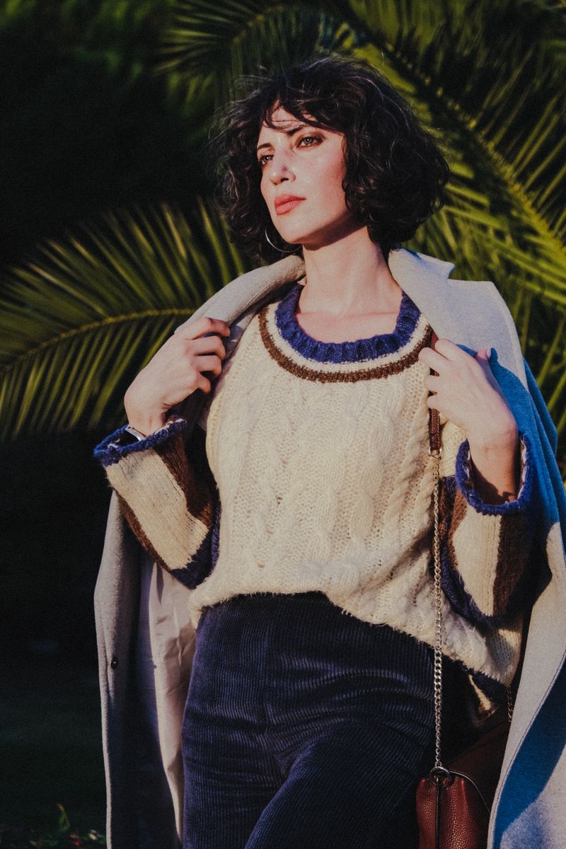 woman in cream fisherman sweater and corduroy trousers