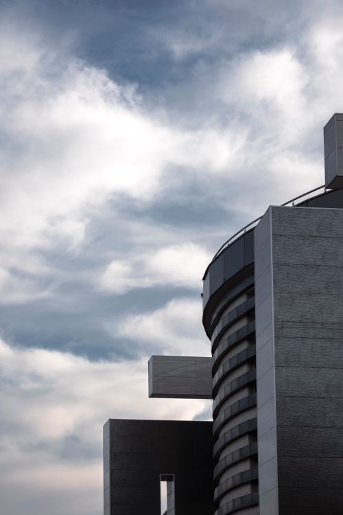 Free Close-up of a concrete building with geometric shapes and a dramatic sky. Stock Photo