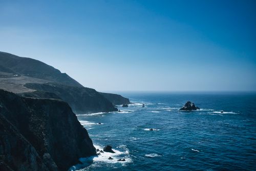 Free Rugged cliffs and deep blue ocean under a clear sky, perfect for coastal inspiration. Stock Photo