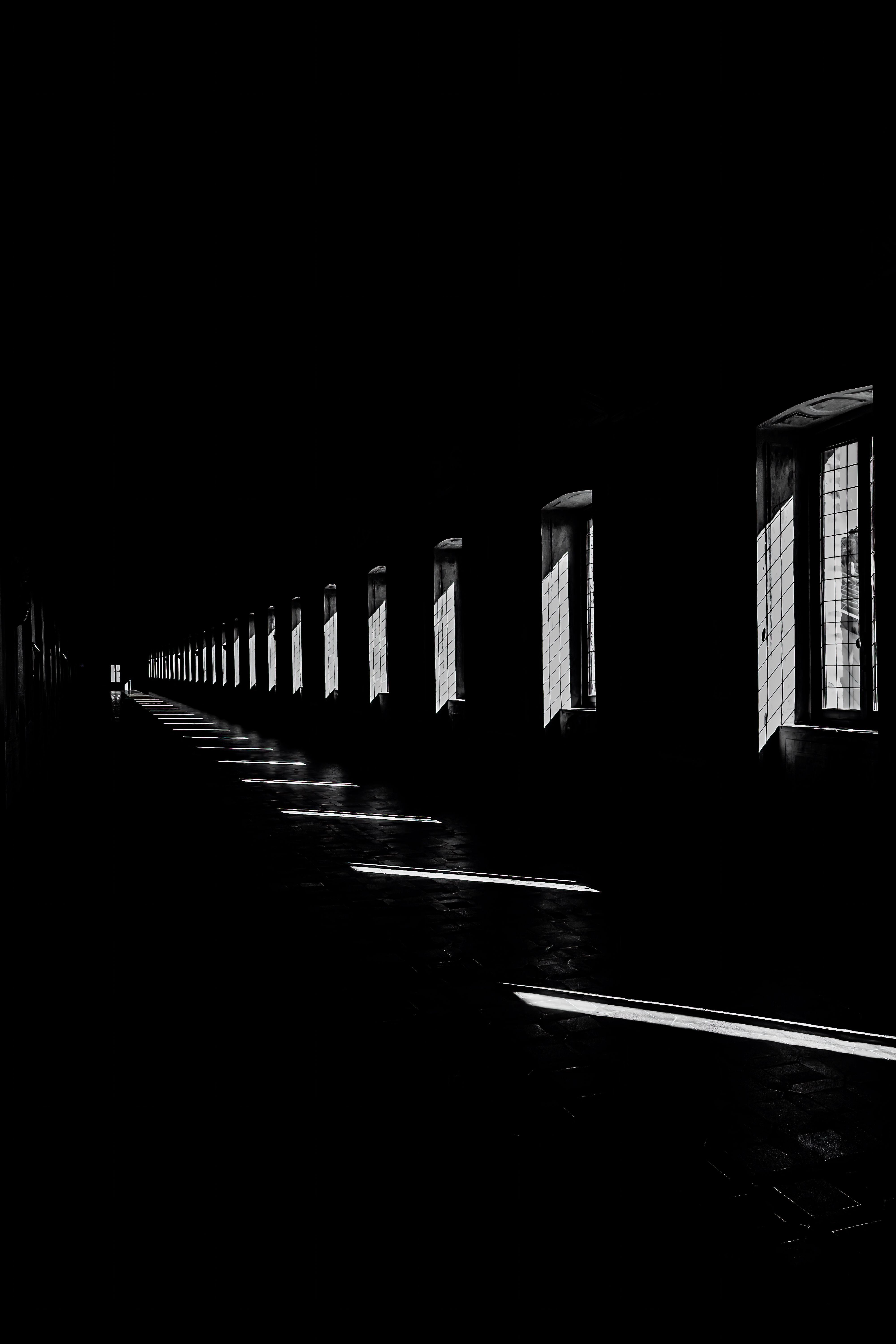 A striking black and white photo capturing light streaming through windows in a long corridor.