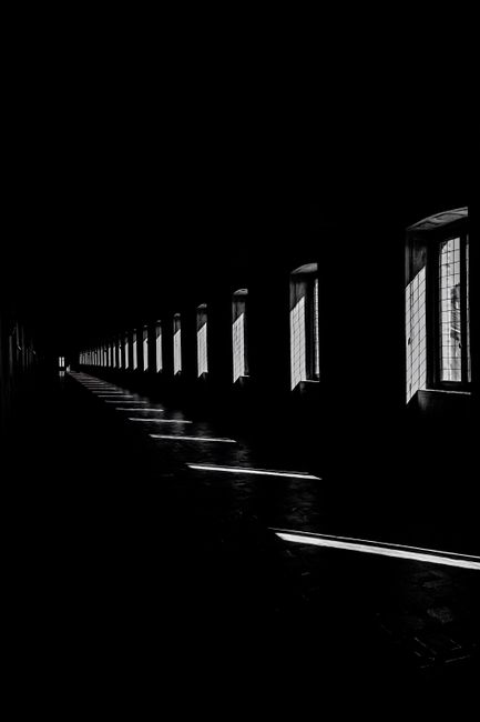 A striking black and white photo capturing light streaming through windows in a long corridor.