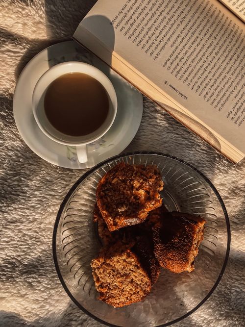 Free A peaceful morning scene with coffee, pastries, and a book in warm sunlight. Stock Photo