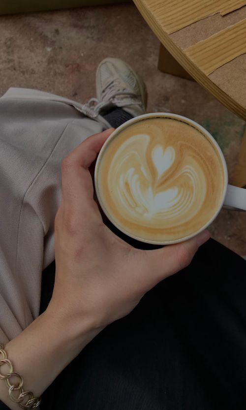 Free Vibrant latte art in a cup held by a person, viewed at a cozy café setting. Stock Photo