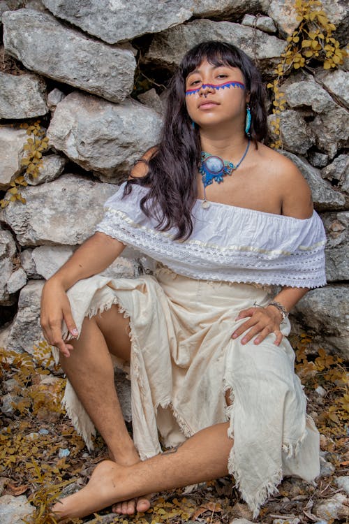 Photo of a Woman Wearing a Summer Dress, Leaning against a Stone Wall