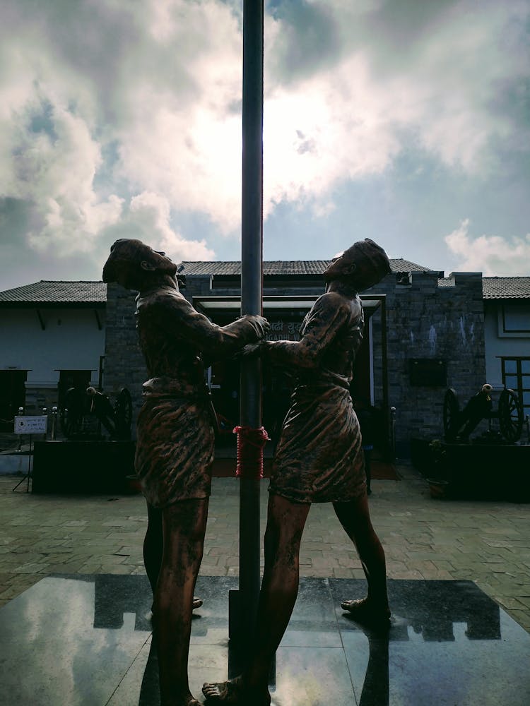 Brown Statues Of Men Near A Pole