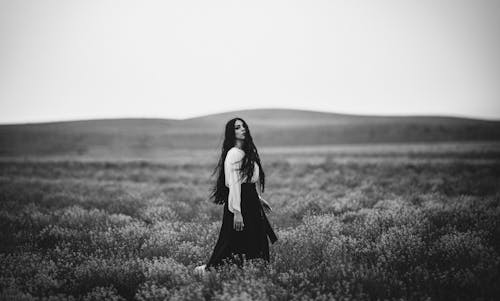 Black and White Photo of Woman Walking in the Field