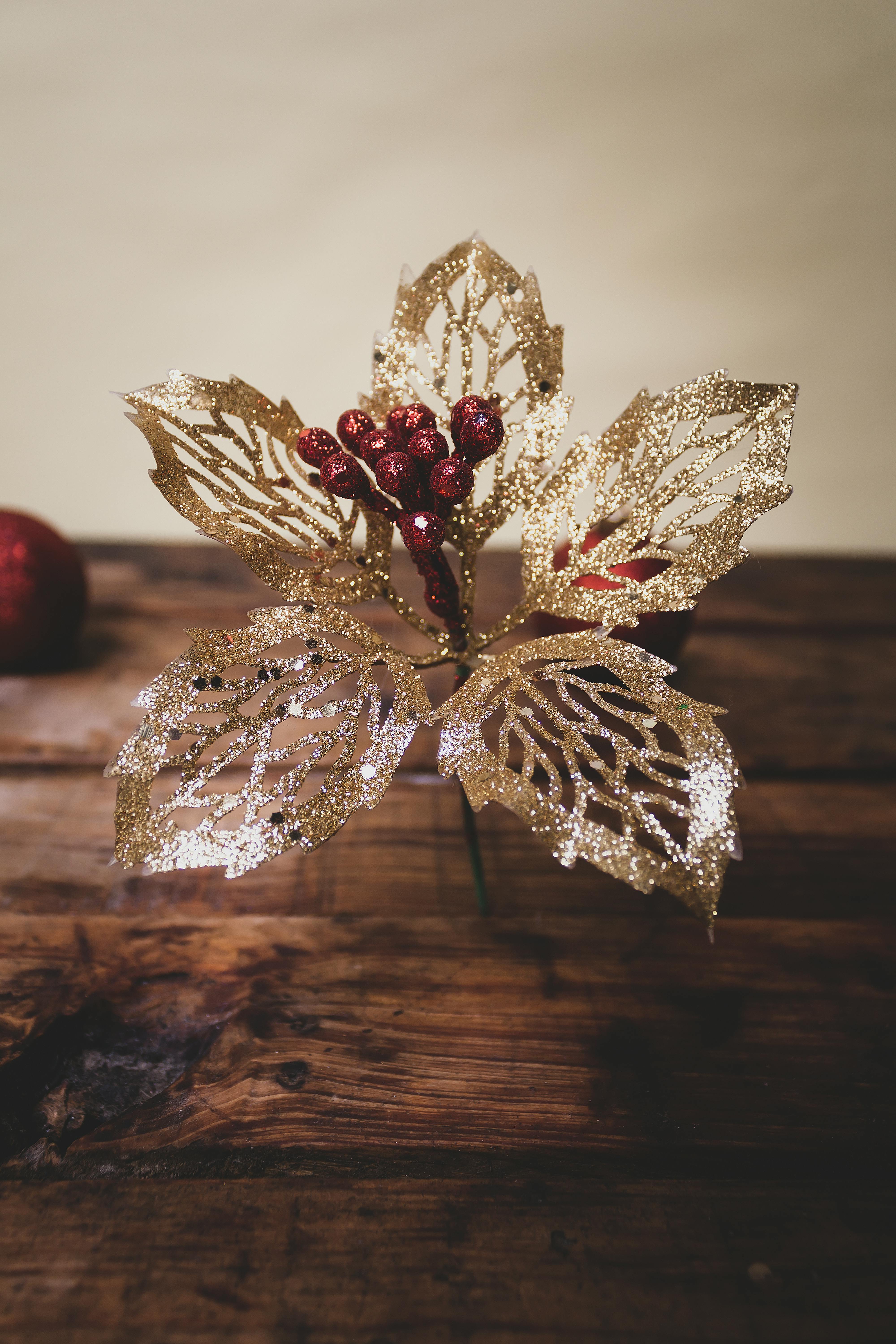 Gold glittering holiday decoration with red berries on a wooden surface, indoor festive scene.
