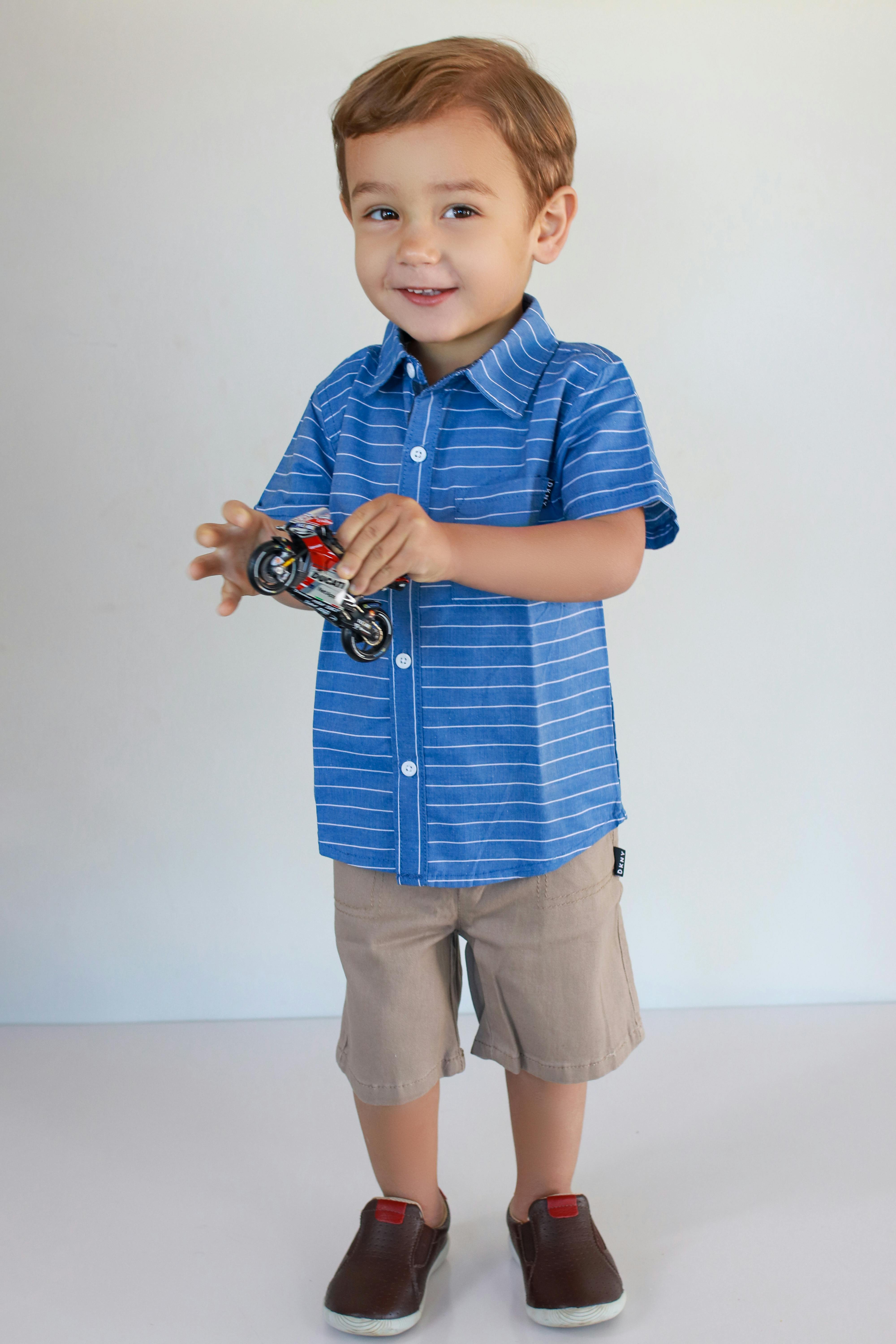 a boy in blue striped shirt holding a toy