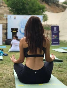 Back view of a woman meditating outdoors on a yoga mat in Göreme, Türkiye.
