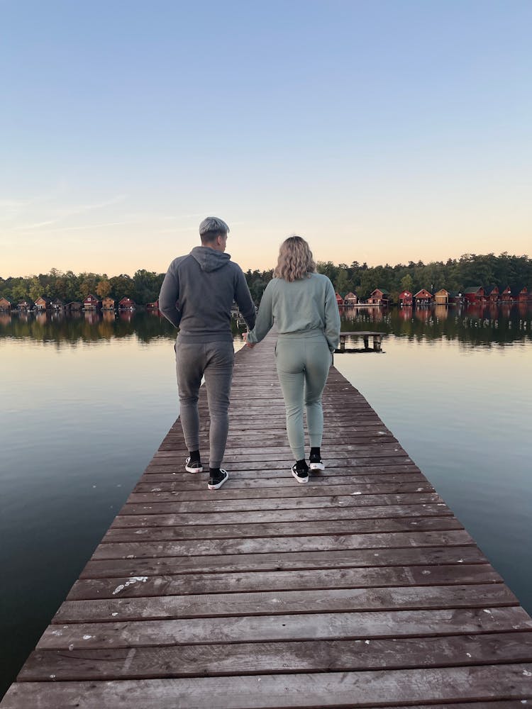 Back View Of A Couple Walking On A Wooden Dock