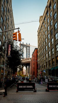 Street view capturing Manhattan Bridge from Washington Street in New York's Dumbo neighborhood, featuring urban architecture.