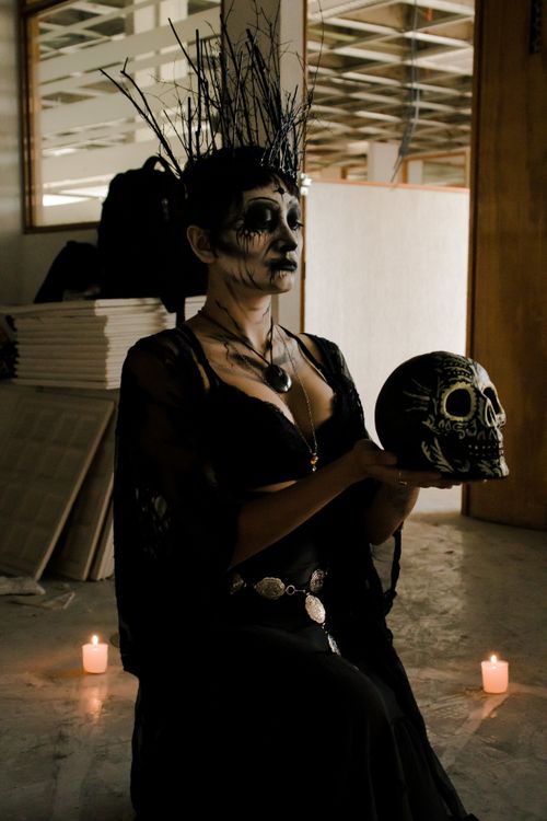 Free Dark, eerie image of a woman in gothic costume holding a decorated skull with candles. Stock Photo