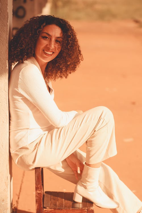 A Smiling Woman with Curly Hair Wearing White Long Sleeves