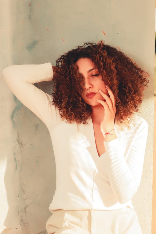 A Woman with Curly Hair Posing with Her Hand Behind Her Head