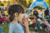 一名年轻女孩的侧面图，在户外活动中，周围都是人