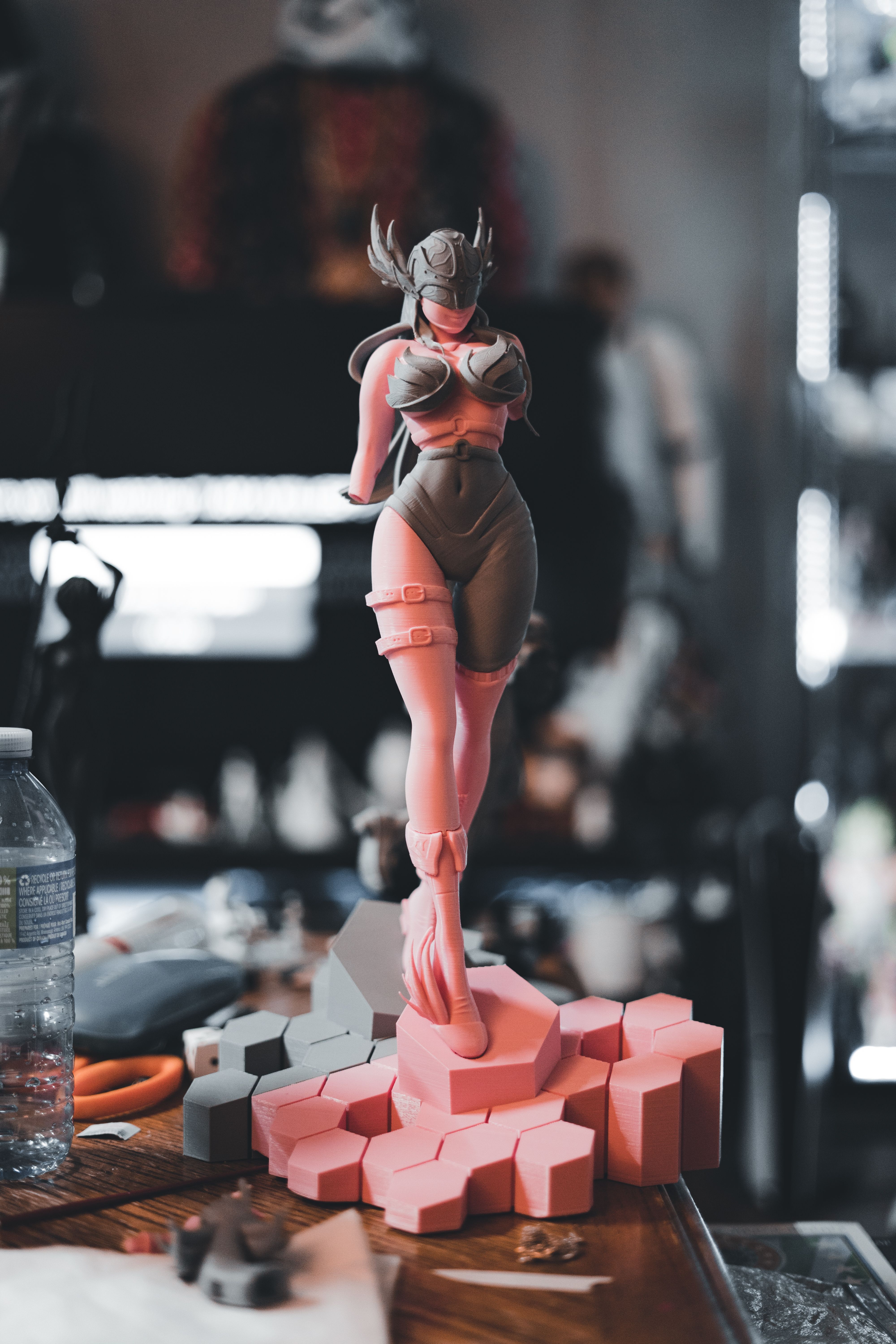 Detailed figurine of a woman in a hero pose, displayed on a table with geometric base.