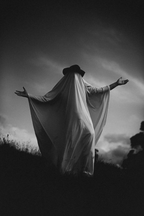 Free A ghostly figure in flowing robes stands in a dramatic monochrome landscape, evoking mystery and intrigue. Stock Photo