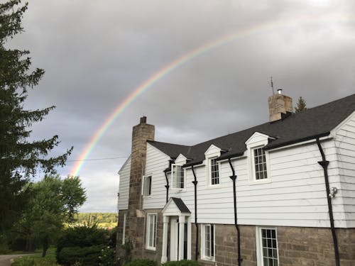 Rainbow above rural cottage in fields