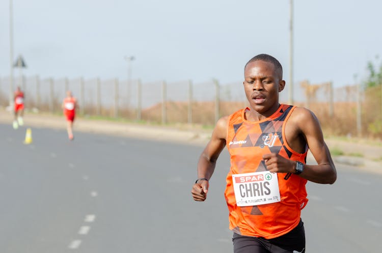 Man In Orange Tank Top Running On A Marathon