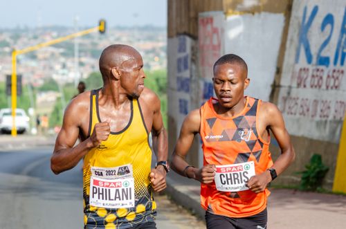 Free Two male athletes running a marathon on city streets wearing tank tops and sportswear. Stock Photo