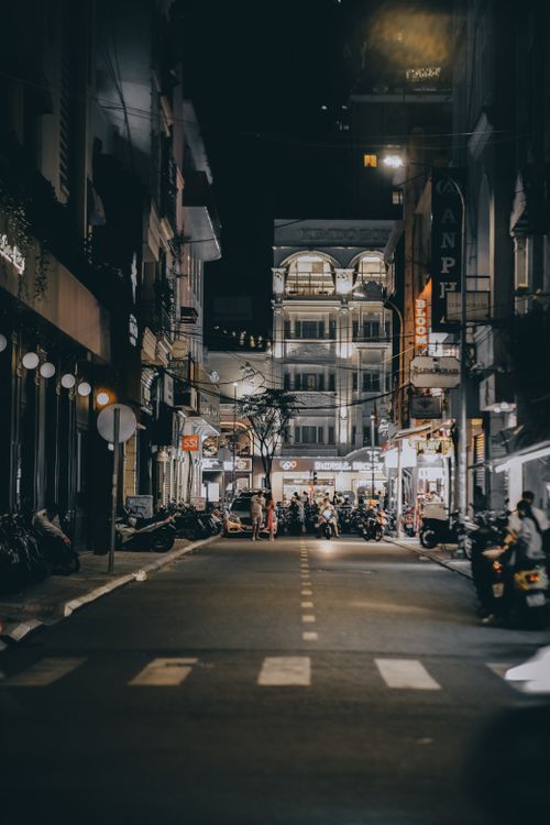 Free A bustling city street at night filled with buildings, cars, and people. Stock Photo