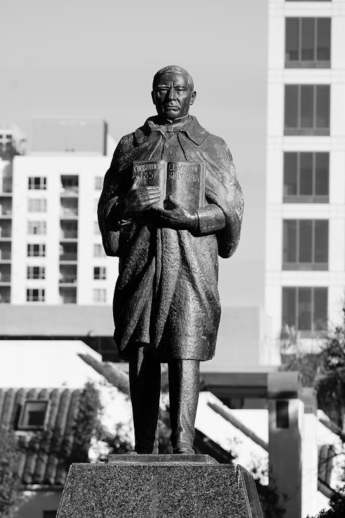Grayscale Photo of a Statue of a Man Holding a Book
