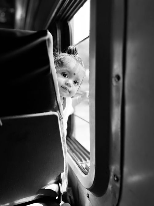 Free Cute baby with bindi peeking inside vehicle in black and white photo. Stock Photo