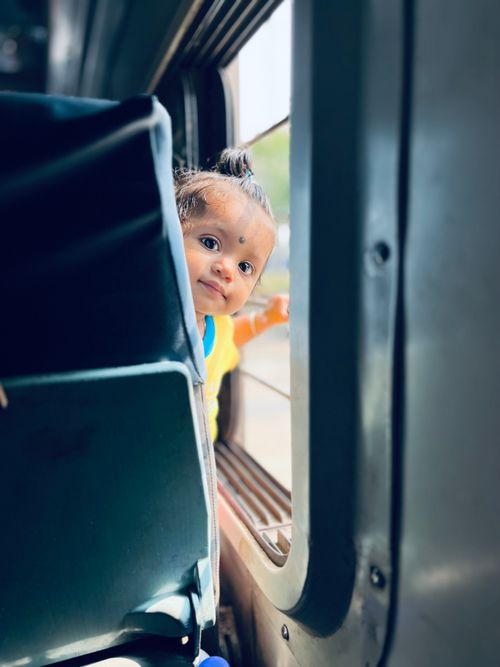 Free Adorable baby peeking through a train window with innocence and curiosity. Stock Photo