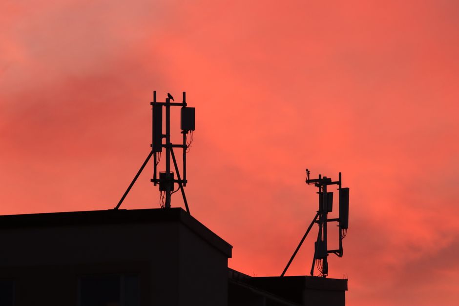 Photo by Efrem Efre on Pexels Silhouetted antennas on building roof against an orange sunset sky creating a striking scene.