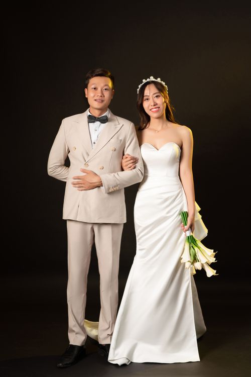 Free Studio portrait of a smiling bride and groom in wedding attire on a black background. Stock Photo