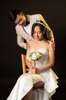 Beautiful wedding couple in studio with bride holding bouquet and groom smiling.