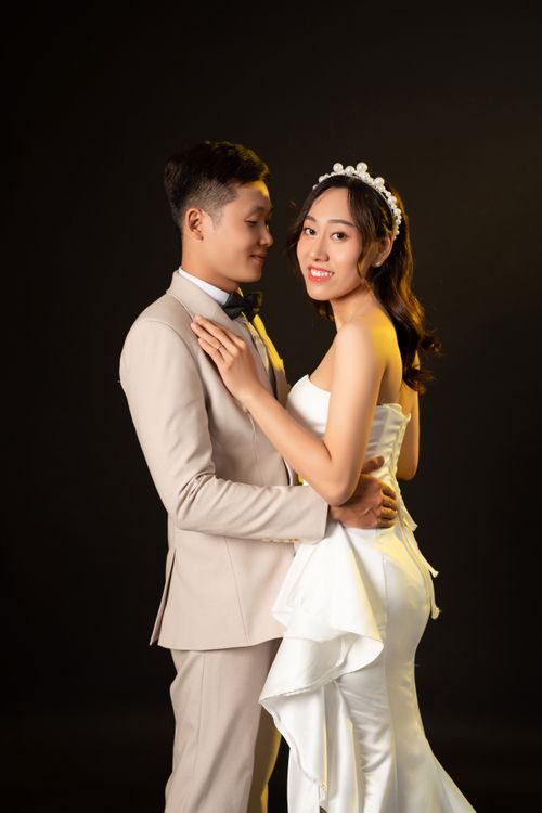 Free Stylish Asian couple posing for wedding photoshoot against a dark background. Stock Photo