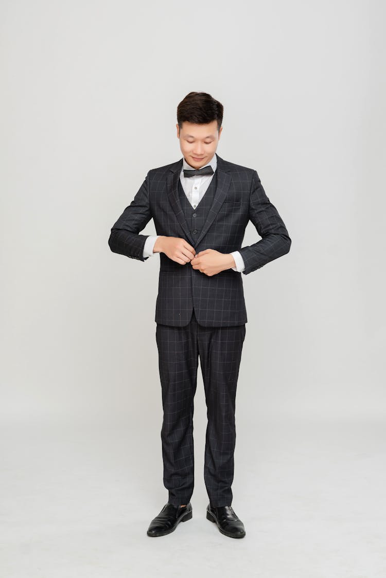 Photo Of A Groom Buttoning His Suit