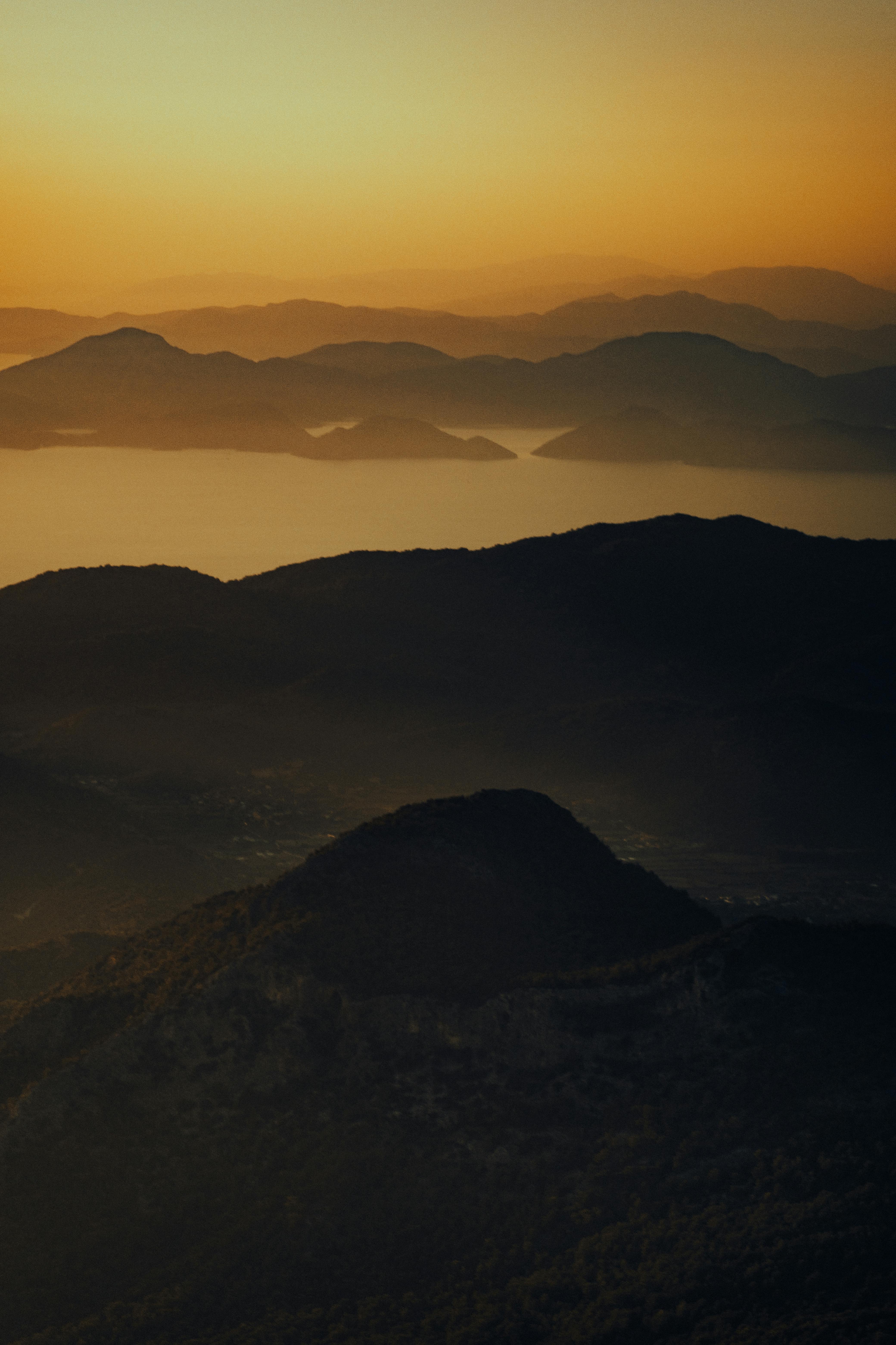 View of serene mountain range during sunset with a warm golden glow.