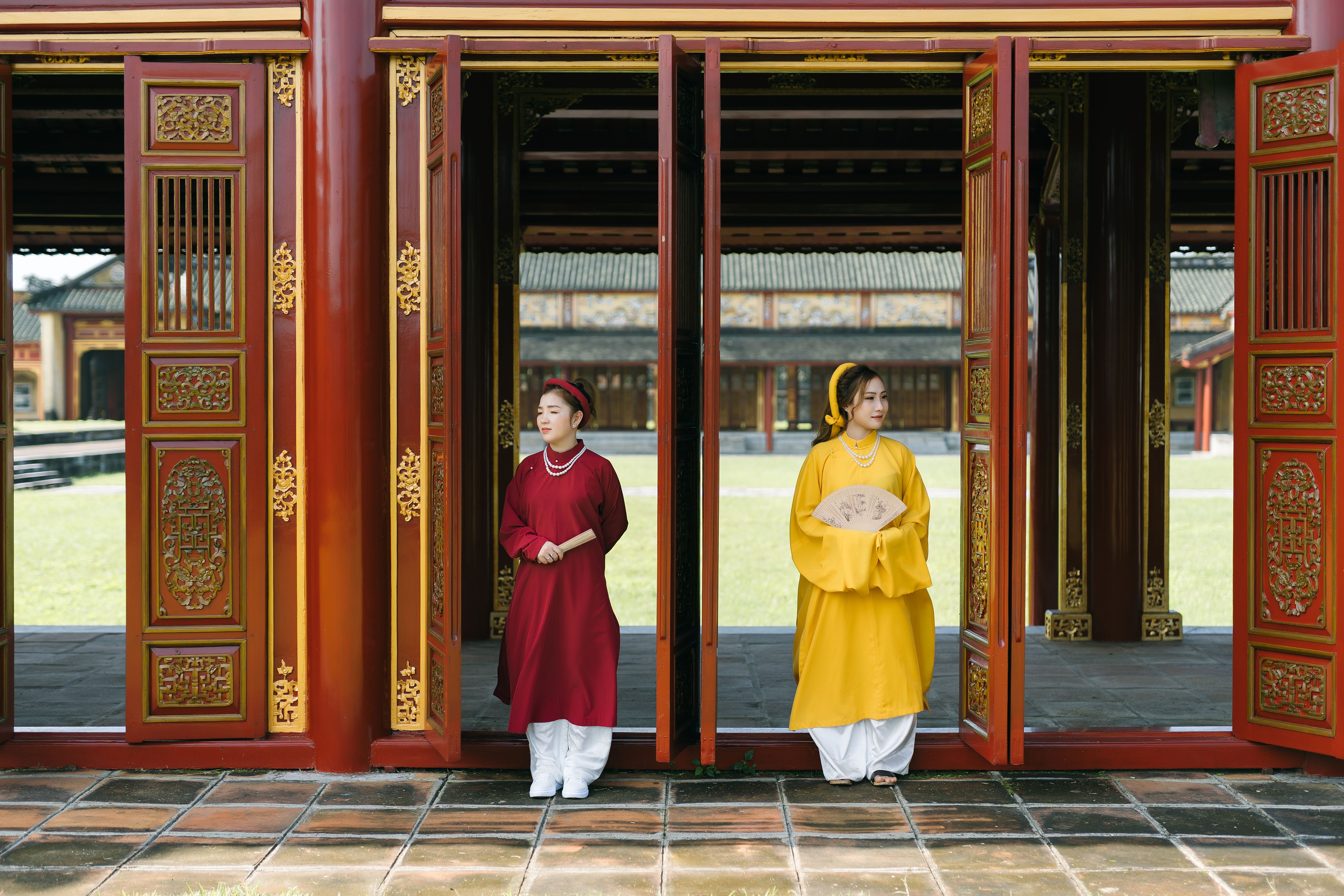 Two women in traditional Vietnamese Ao Dai dresses standing in a temple doorway